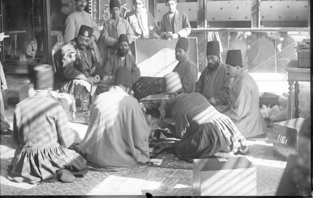در اینجا تصویر خاص و متفاوتی از ناصرالدین شاه قاجار را ملاحظه می‌کنید که او را به همراه جمعی از درباریان در حال بررسی اشیاء ارزشمند موجود در خزانه سلطنتی نشان می‌دهد.