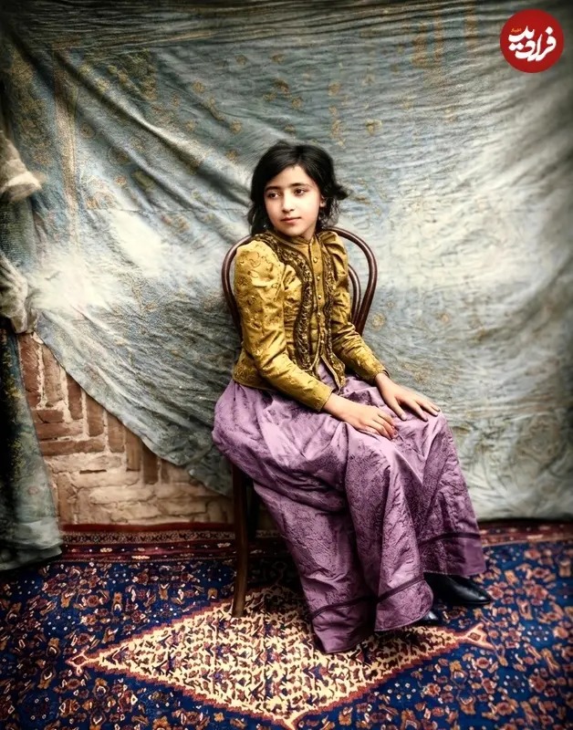 در اینجا عکسی از دوران قاجار را ملاحظه می‌کنید که یک دختر نوجوان را نشسته بر روی صندلی در مقابل پرده‌ای رنگی و روی یک قالی به تصویر کشیده است.
